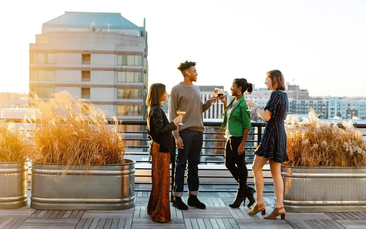 Friends toast drinks on a rooftop patio, enjoying the sunset. Perfect for finding things to do in Durham, NC this weekend.