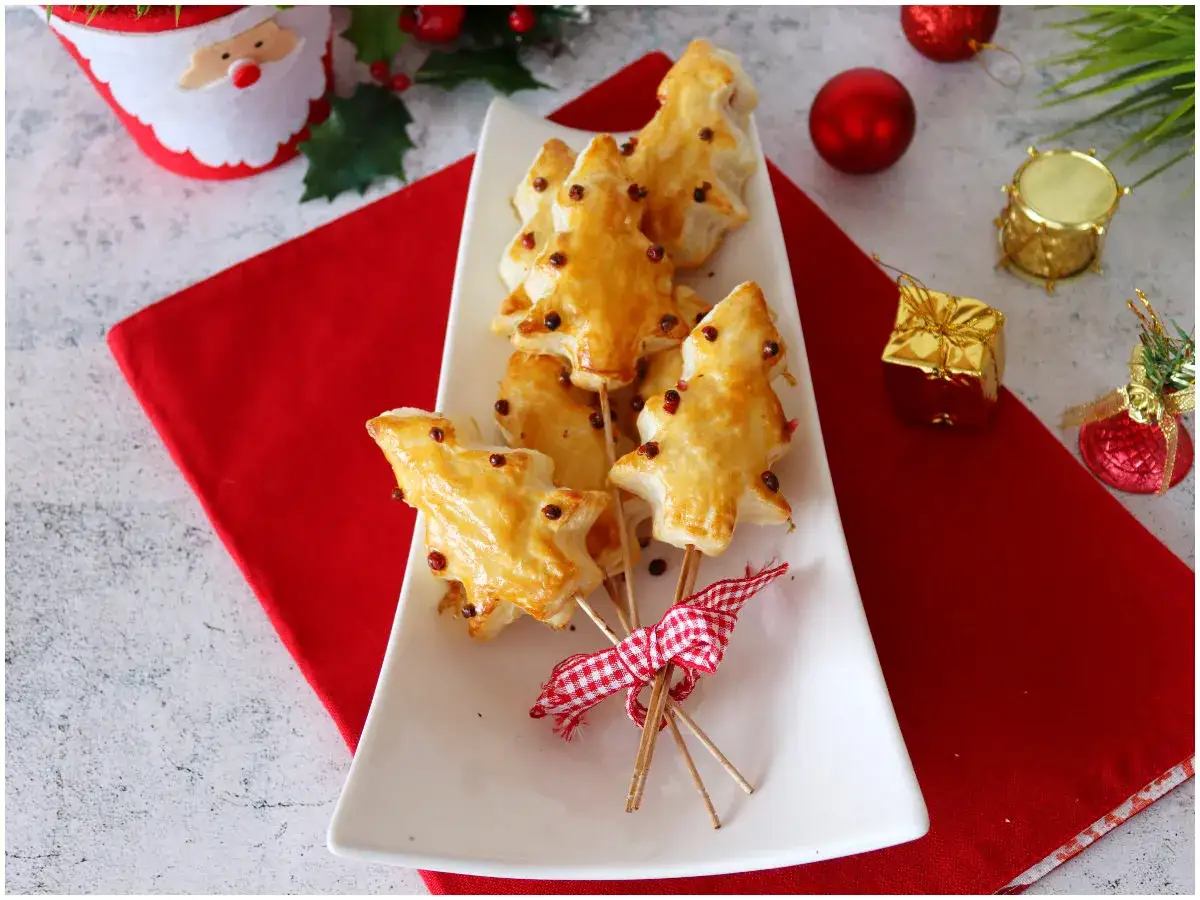 Alberelli di sfoglia dorata, perfetti antipasti di Natale, decorati con bacche rosse e legati con un nastro a quadretti.