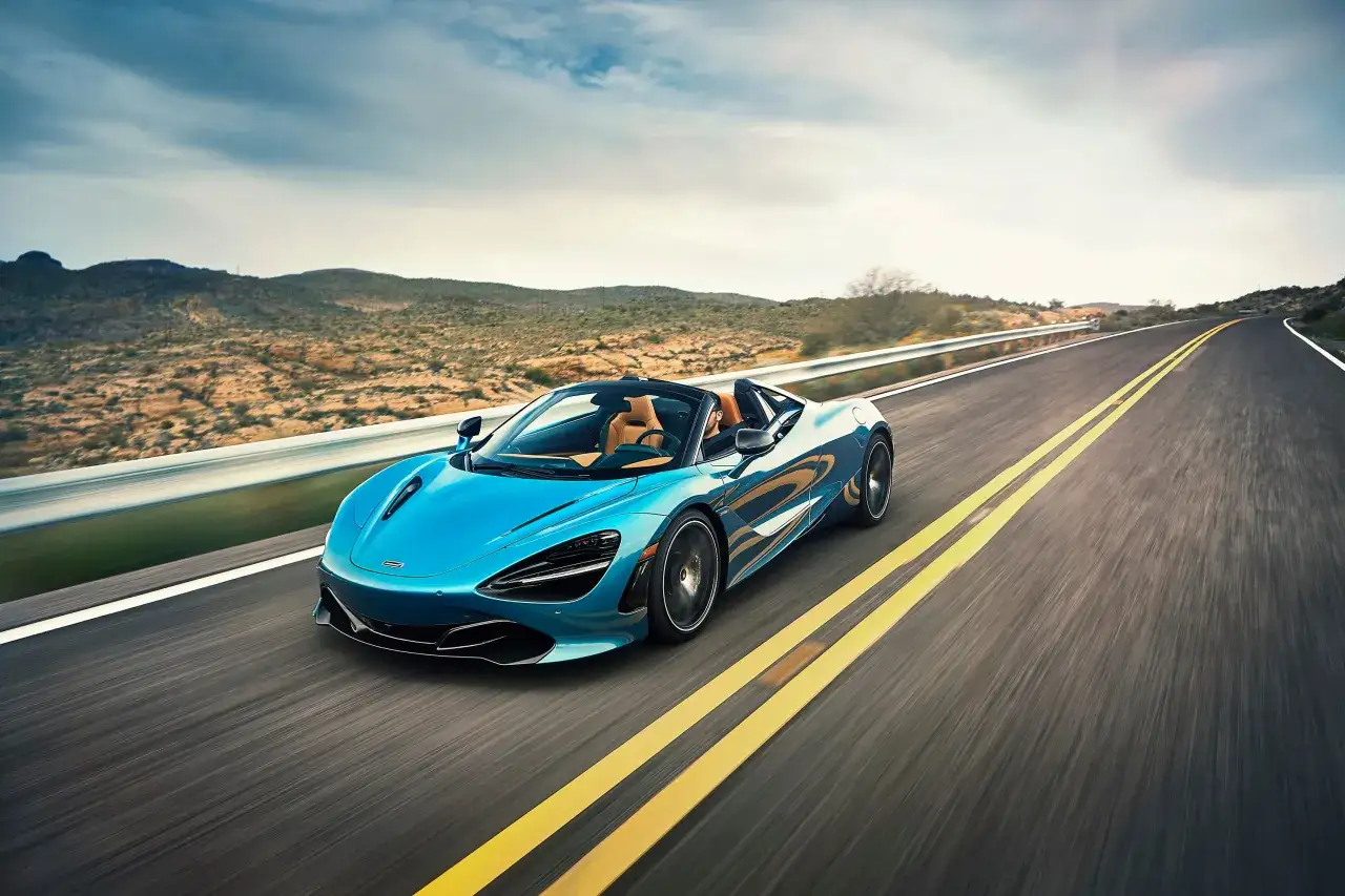 Błękitny McLaren 720S sunie po pustynnej drodze, ukazując swoje sportowe linie.