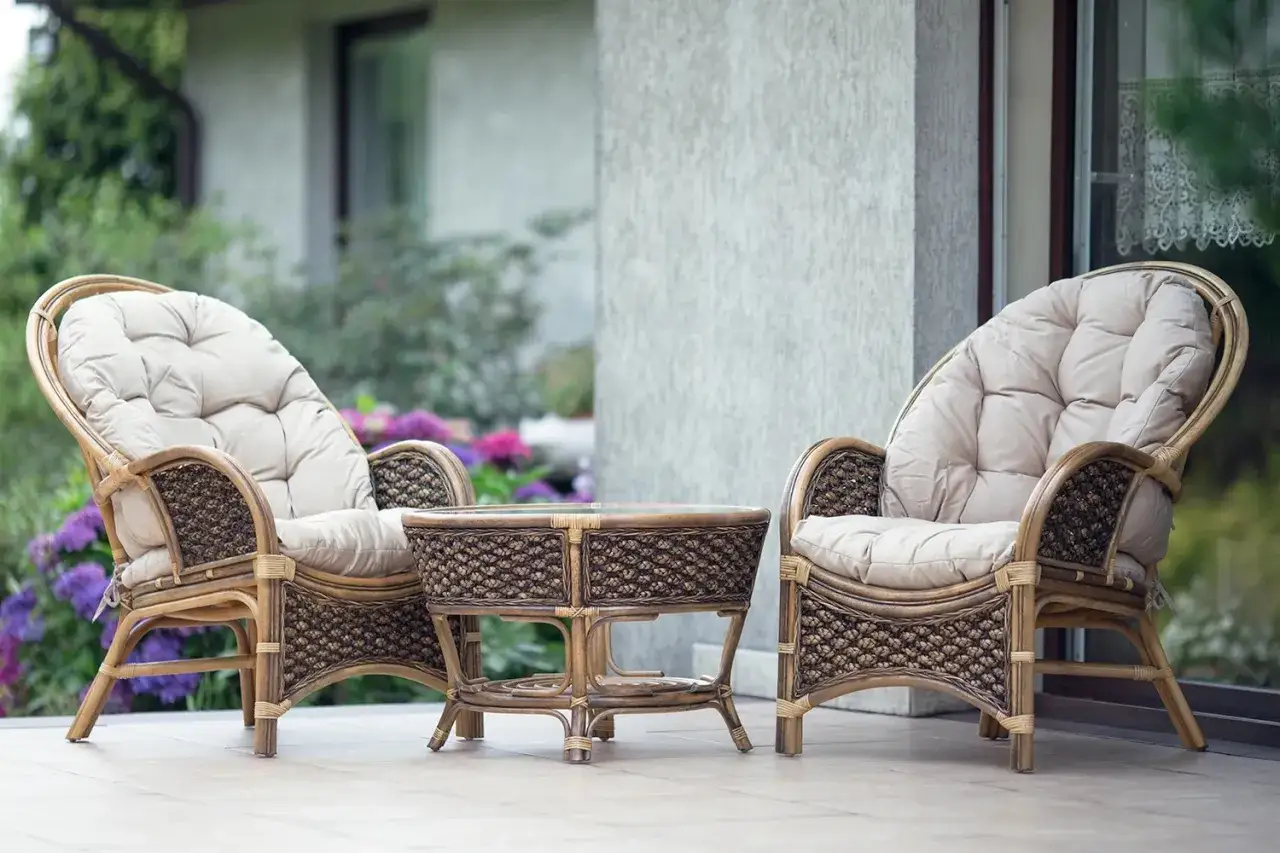 Dwa fotele i stolik kawowy z plecionki rattanowej, idealne na taras. Rattan to naturalny materiał, który nadaje meblom lekkości i elegancji.