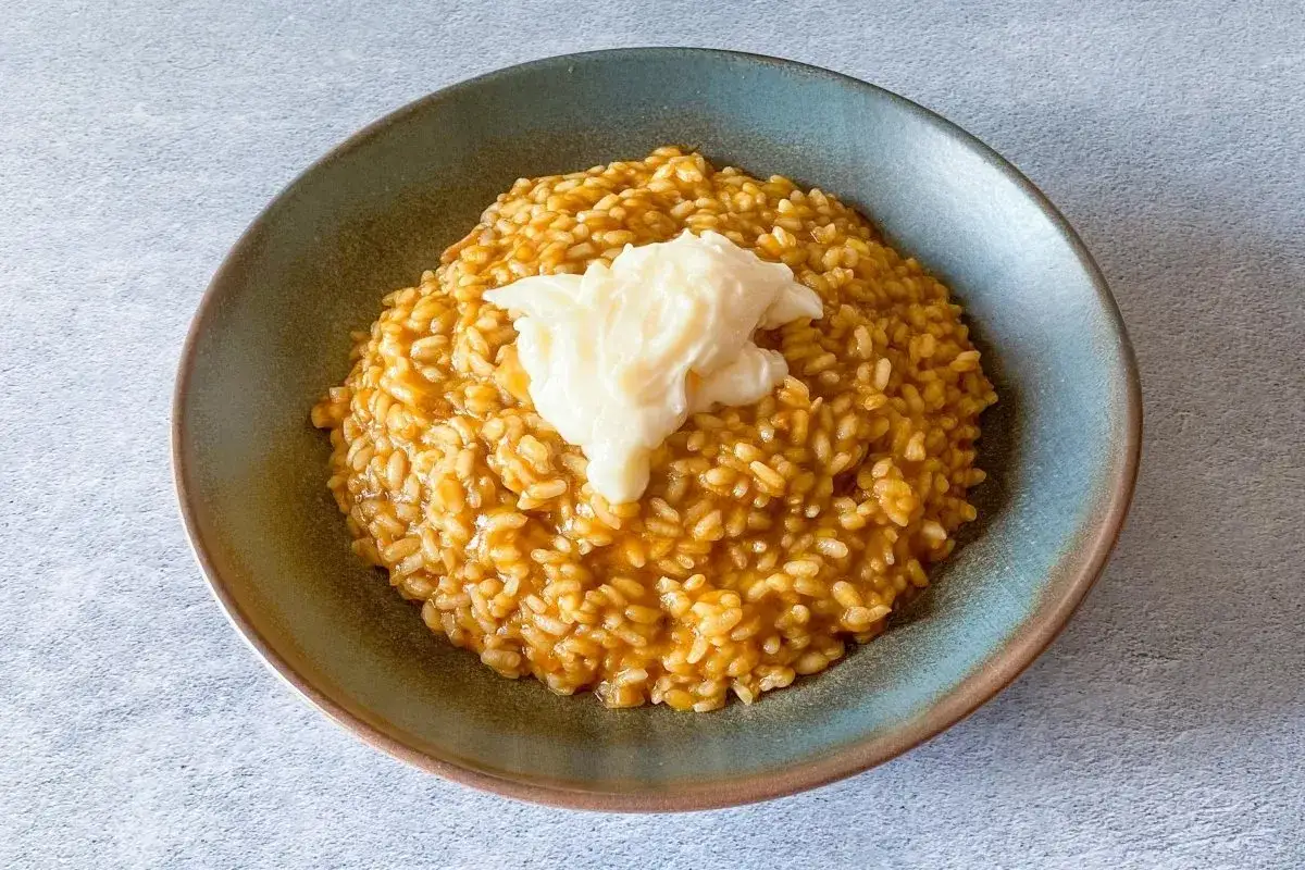 Un cremoso caldero murciano, con su arroz dorado y una quenelle de alioli, listo para ser disfrutado.