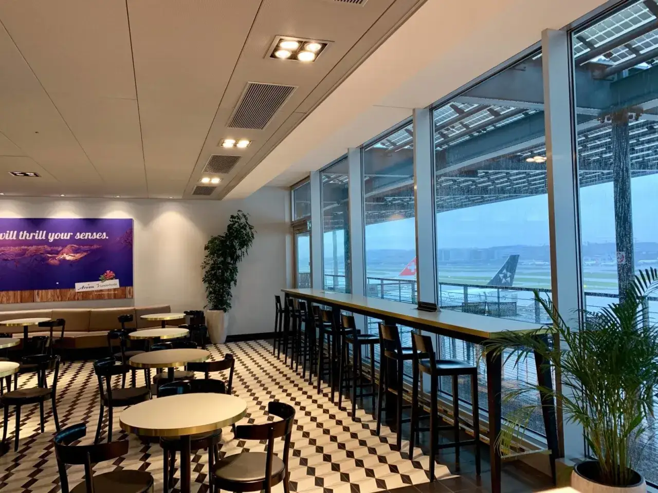 Gemütliche Lounge mit Blick auf das Flugfeld. Die **Priority Pass Vorteile** sind hier offensichtlich: Komfort, Ruhe und ein guter Platz, um die Aussicht zu genießen.