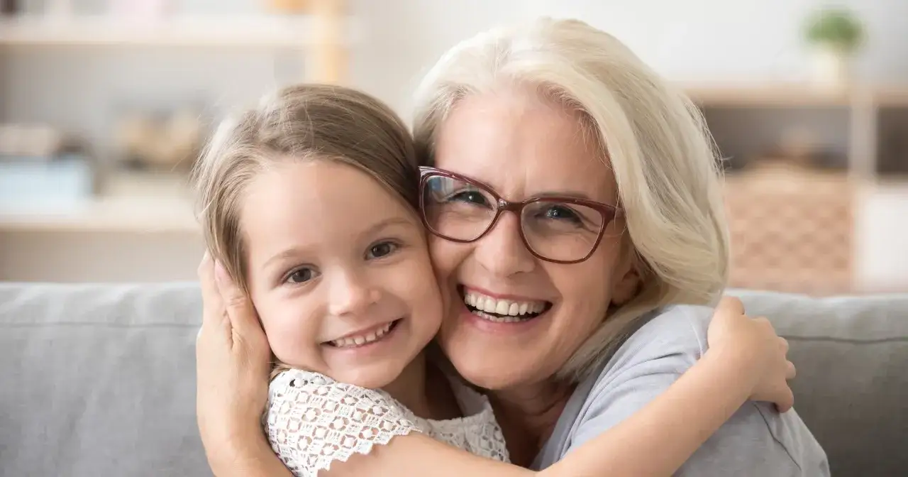 Uśmiechnięta babcia obejmuje wnuczkę. To obraz szczęśliwej rodziny, symbolizujący zasłużoną emeryturę dla matek 4 dzieci, które pracowały.