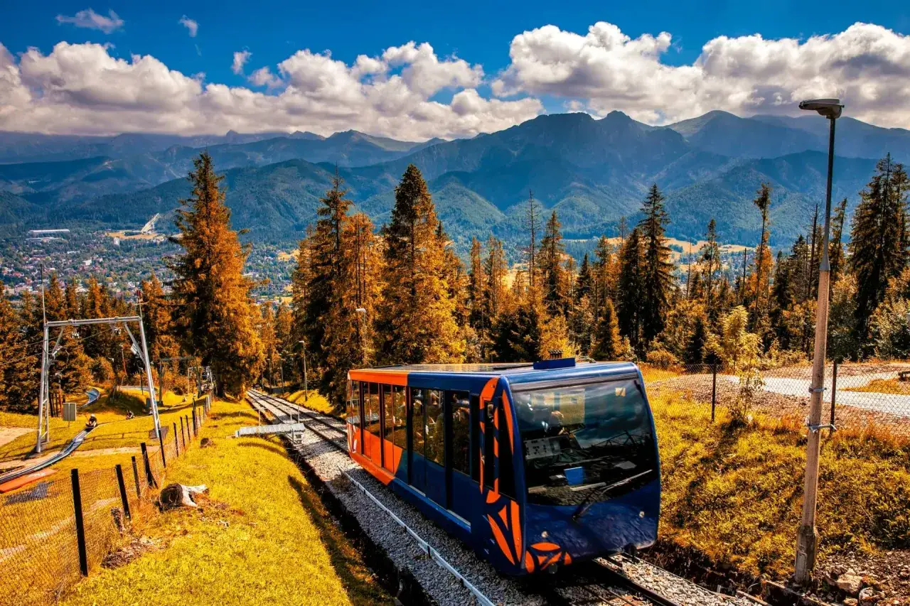 Kolejka na Gubałówkę w jesiennej odsłonie. W tle malownicze Tatry, a obok tor saneczkowy. Gubałówka atrakcje zachwycają!