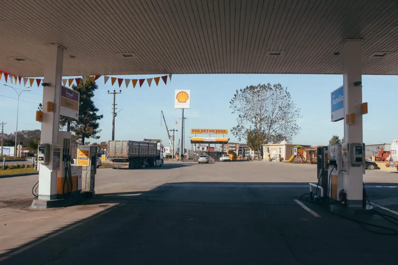 Stacja paliw z dystrybutorami na diesel i benzynę. W tle ciężar&oacute;wka i samochody.
