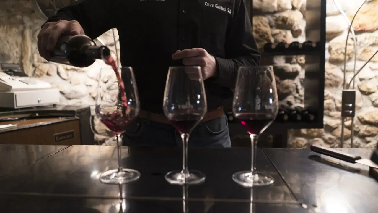 Un homme verse du vin rouge dans trois verres. La dégustation révèle la douceur du sucre dans le vin.