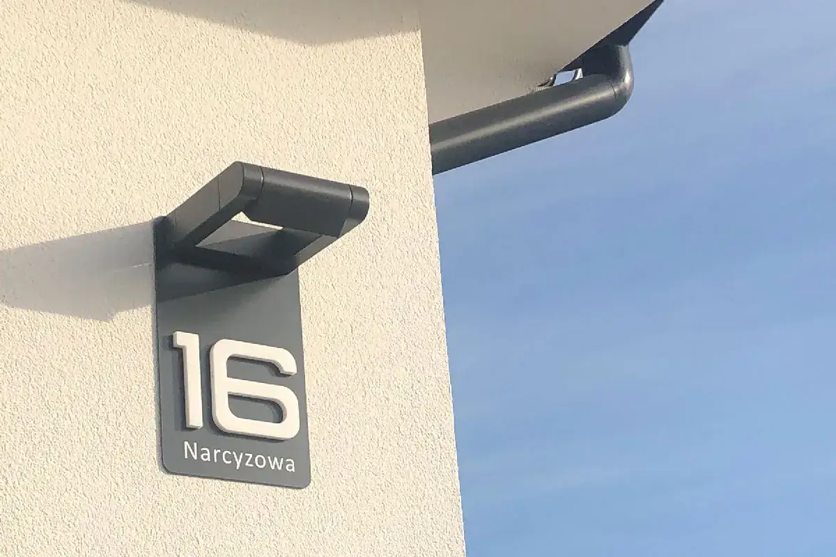 Nowoczesny szyld z numerem 16 i nazwą ulicy Narcyzowa. To jest numer lokalu, który ułatwia odnalezienie domu.