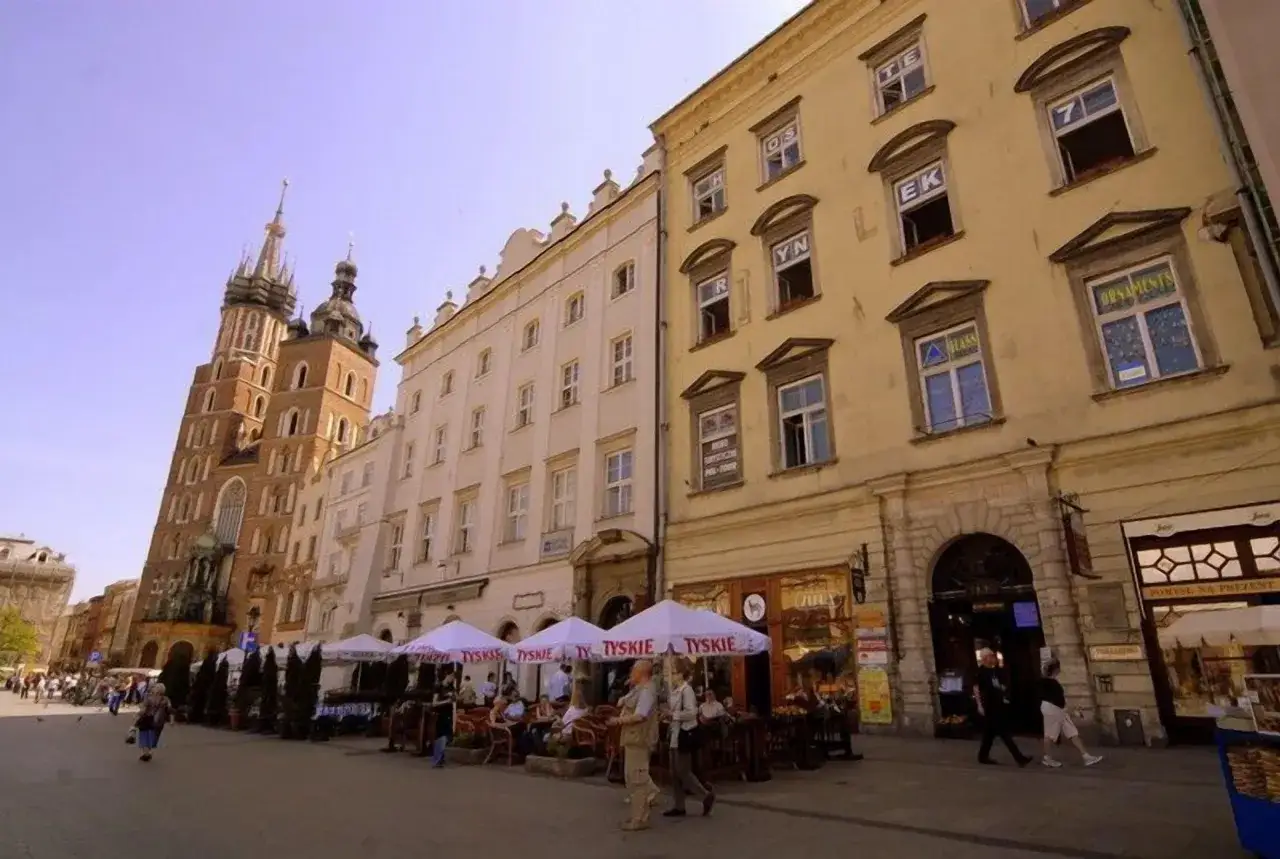 Spacerem po Rynku Głównym w Krakowie, zastanawiając się, ile kosztuje nocleg w Krakowie, mijam kawiarnie i zabytkowe kamienice.