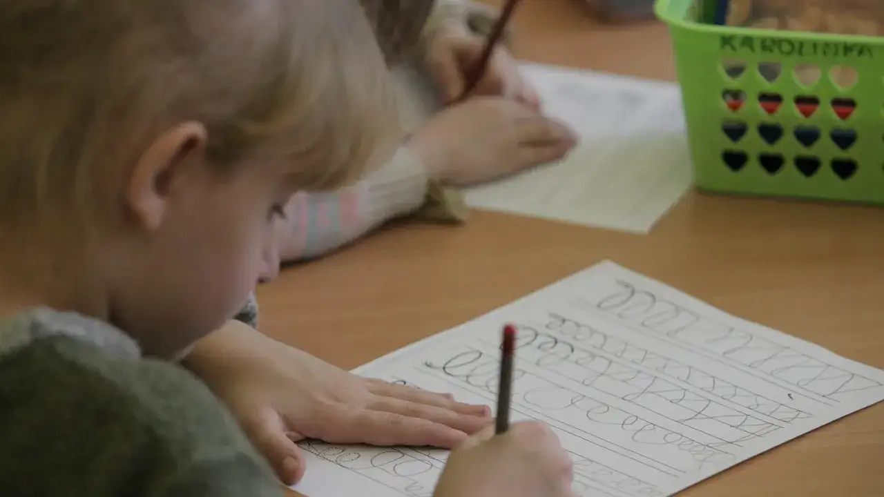 Dzieci ćwiczą pisanie na karcie pracy, co to jest zerówka, przygotowując się do szkoły.