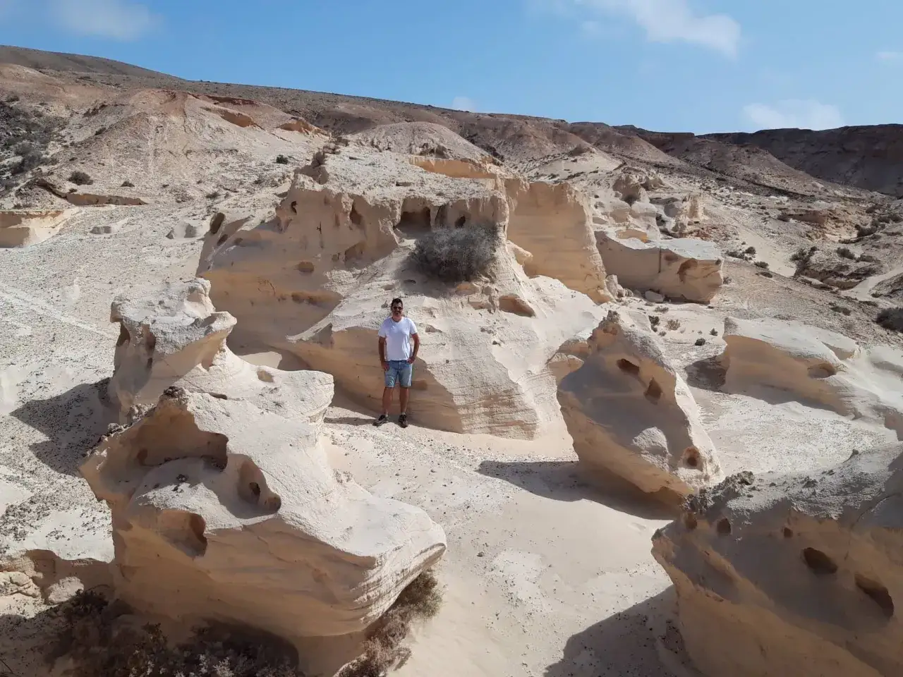 Un hombre posa entre formaciones rocosas erosionadas, un paisaje desértico ideal para explorar entre los 10 sitios para visitar en Fuerteventura.
