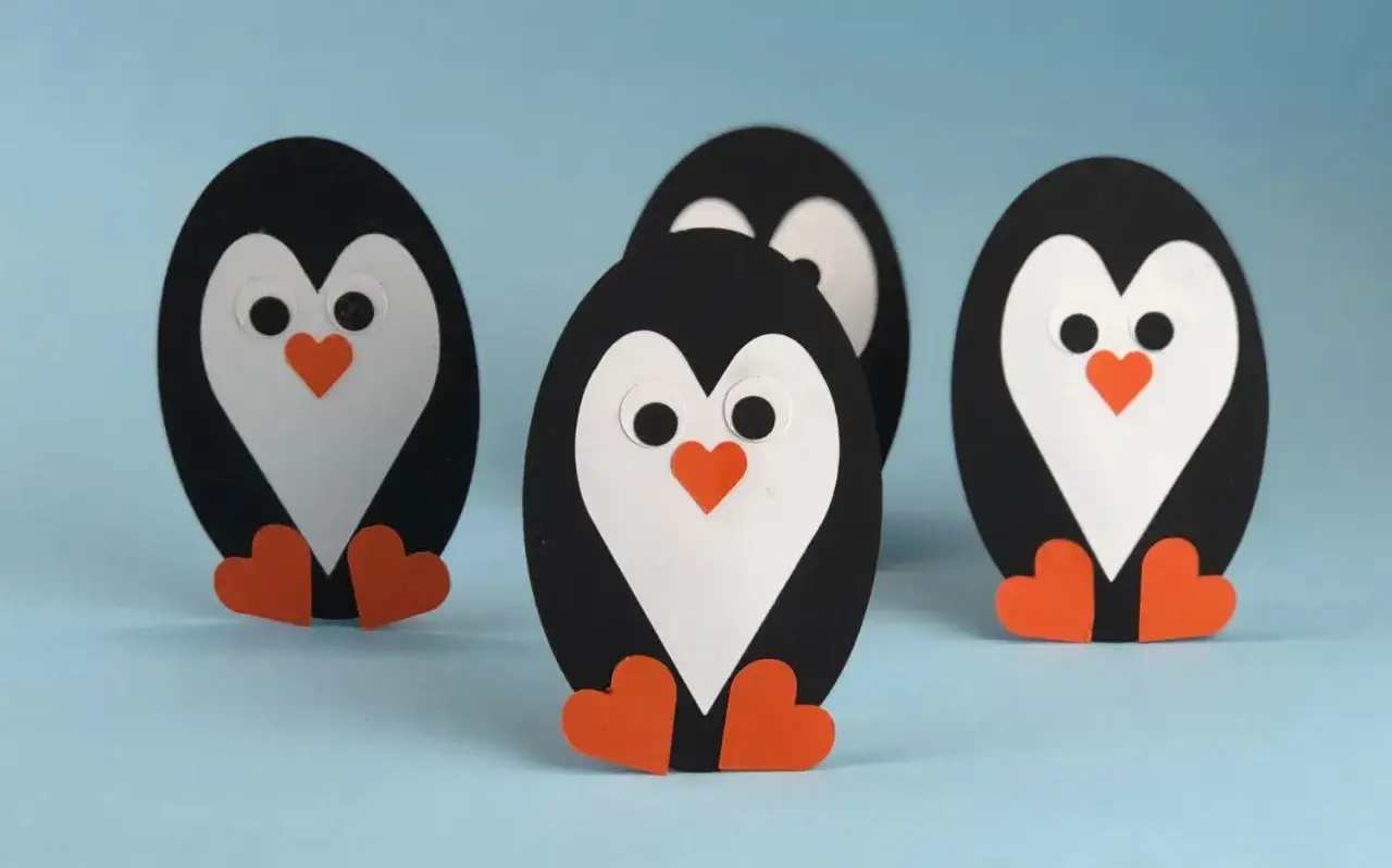 Vier süße Papierpinguine, die zum **Pinguin basteln** einladen. Sie stehen auf hellblauem Untergrund.