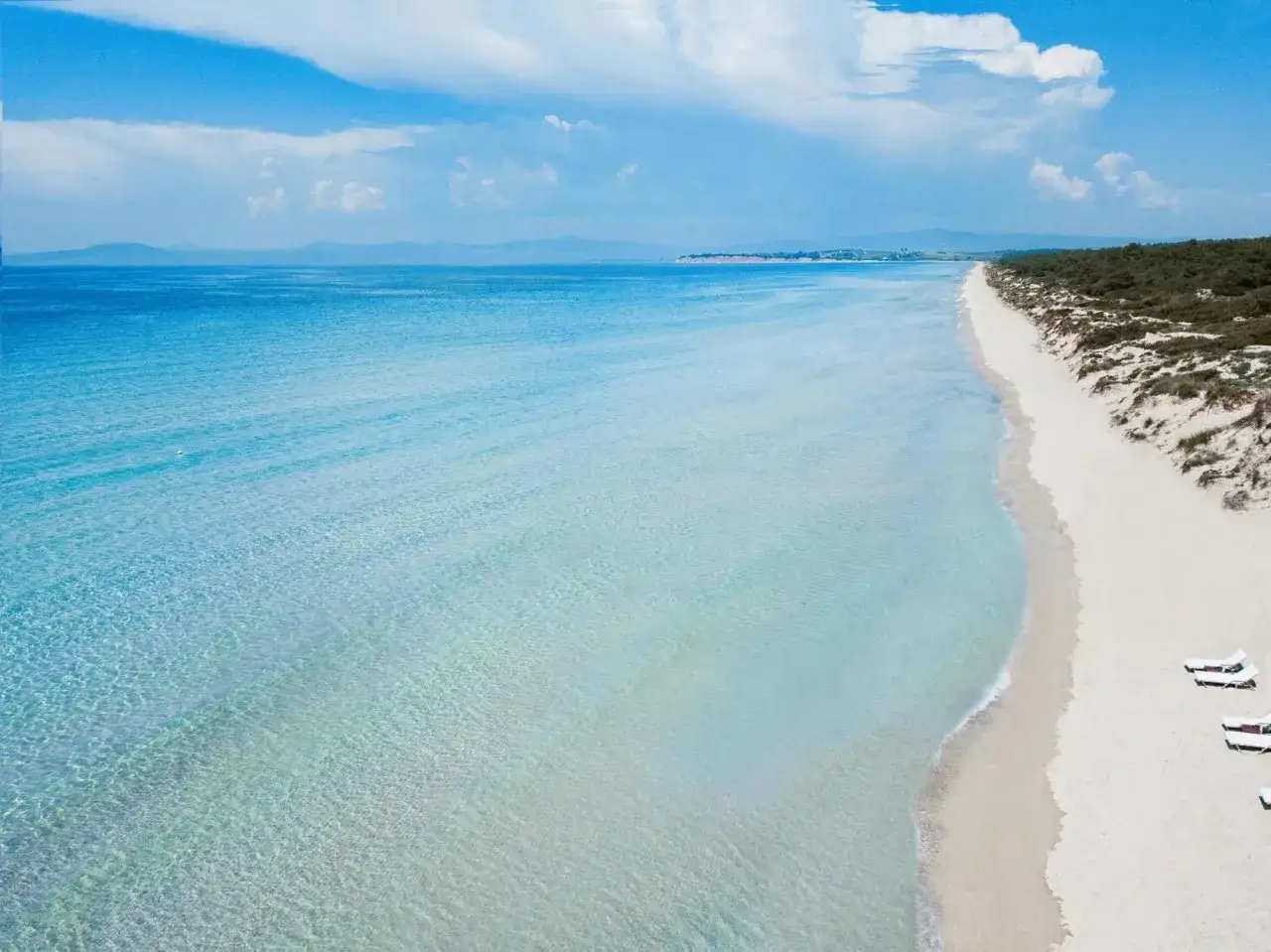 Traumhafter Karibik-Strand auf Chalkidiki mit t&uuml;rkisblauem Wasser, wei&szlig;em Sand und Liegest&uuml;hlen.