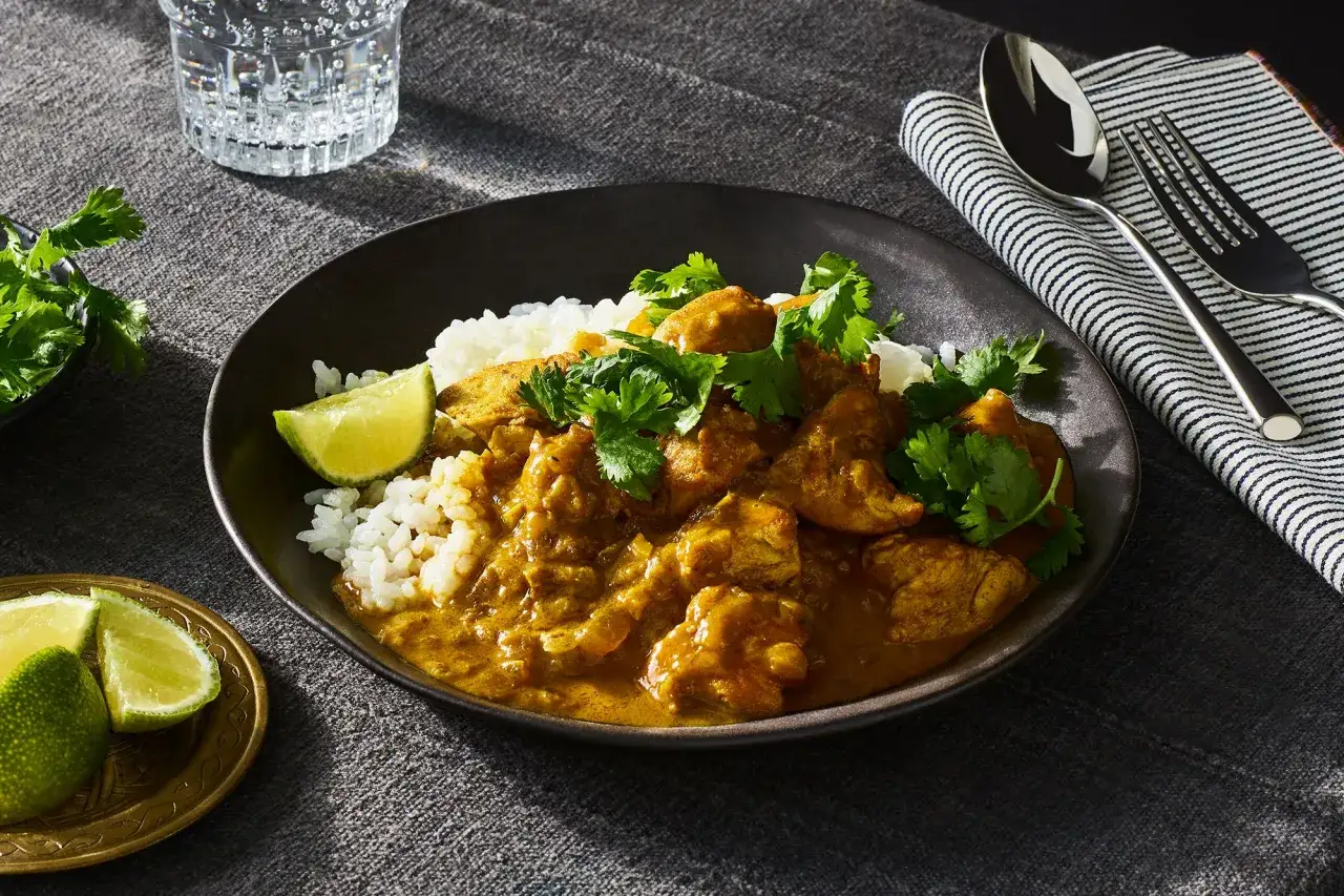 Aromatyczny kurczak w sosie curry z ryżem, świeżą kolendrą i ćwiartkami limonki. Idealny na szybki obiad.