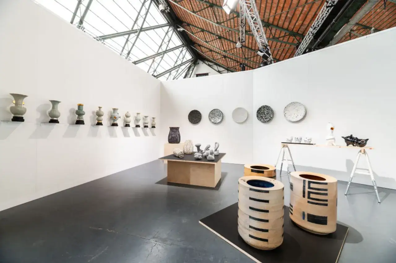 A contemporary art exhibition at the praxis gallery, featuring ceramic vases, decorative plates, and sculptural pieces.