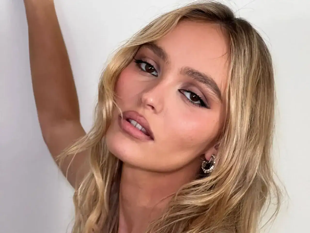 Blonde Frau mit einer stilvollen Frisur, die wenig Haare betont. Ihr Blick ist intensiv, die Lippen leicht geöffnet.