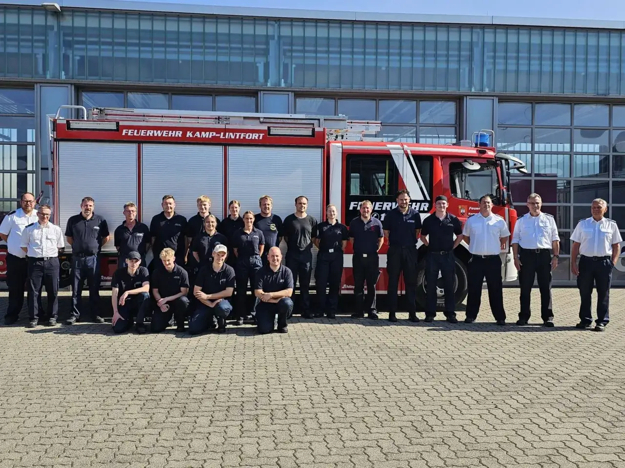 Eine Gruppe von Feuerwehrleuten steht vor einem roten Feuerwehrauto. Der Beruf des Feuerwehrmanns ist wichtig f&uuml;r die Sicherheit.