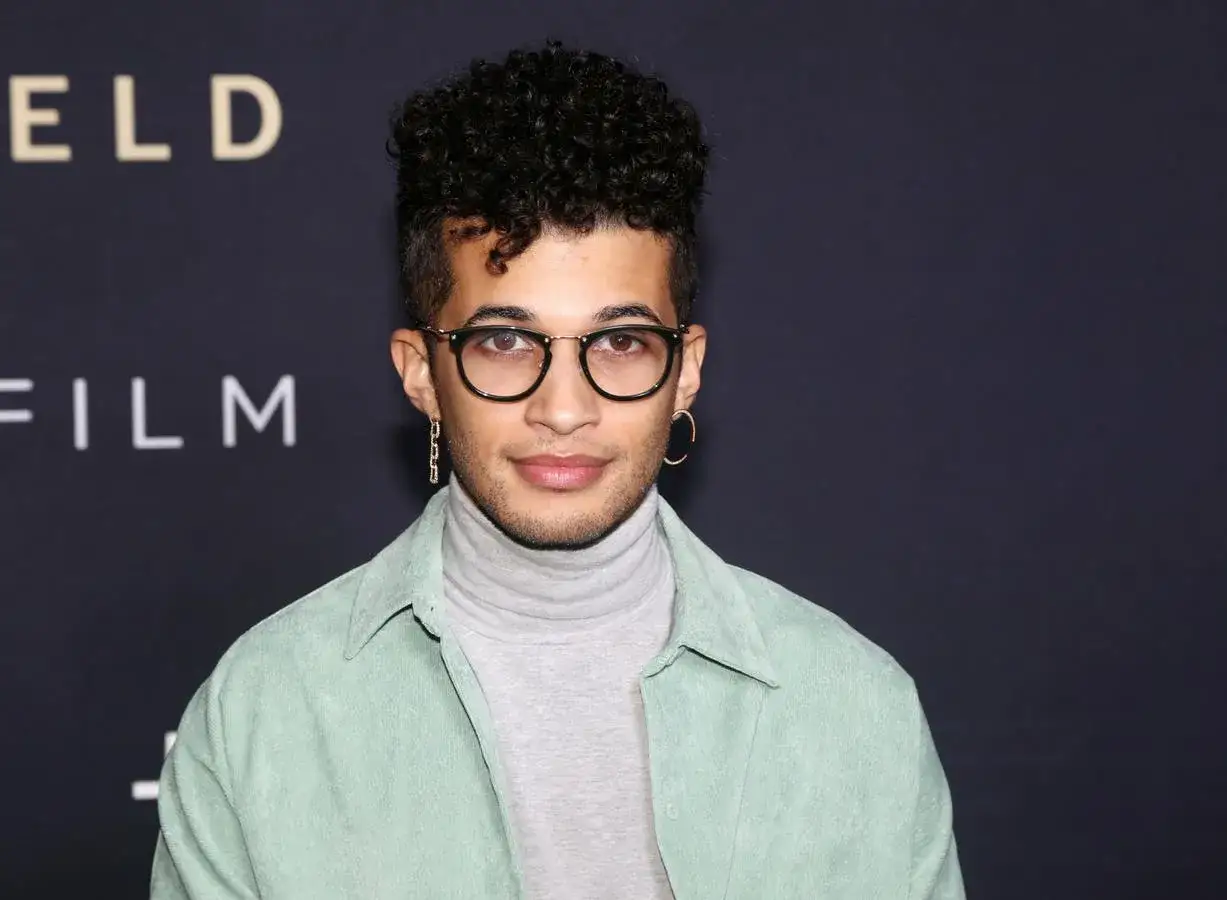 Jordan Fisher, star de films et s&eacute;ries tv, porte un col roul&eacute; gris et une chemise vert menthe.