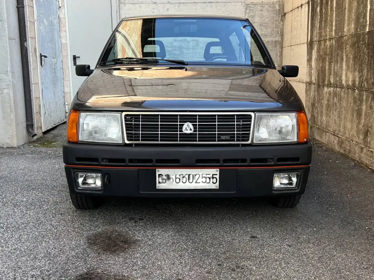 Un'auto d'epoca, una Fiat Uno Turbo diesel, con la sua griglia iconica e i fari squadrati.