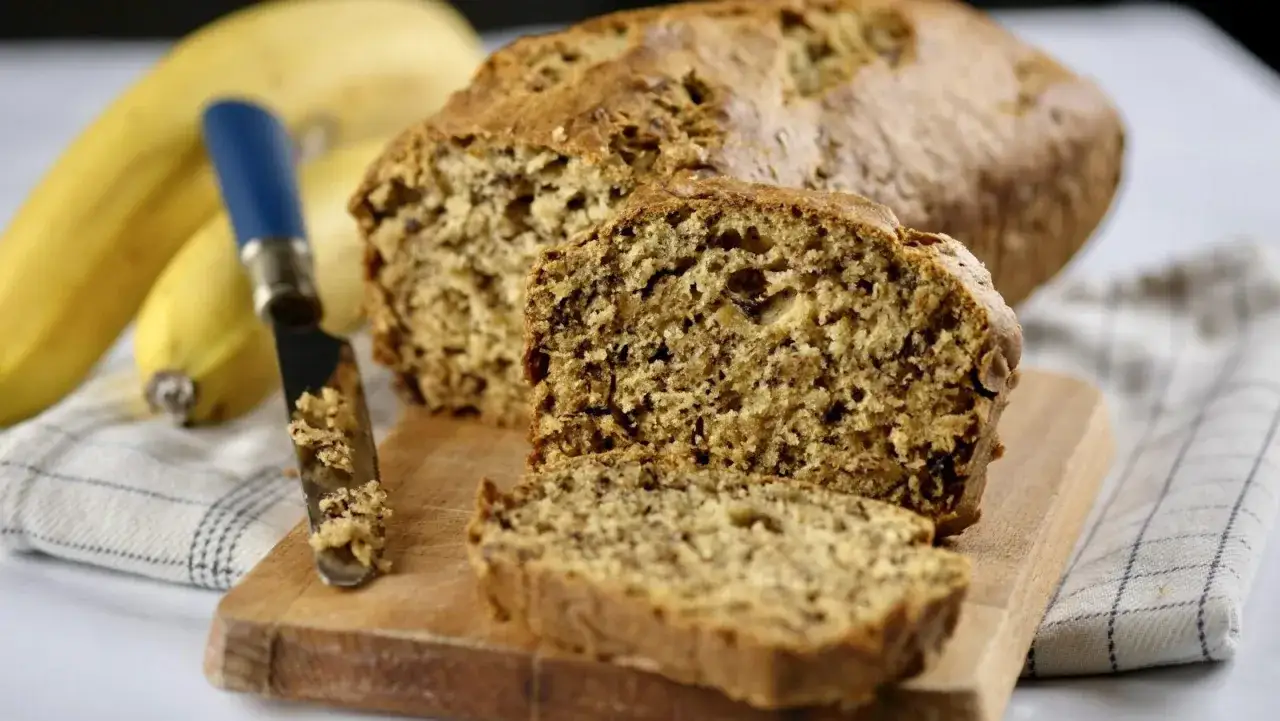 Pyszny chlebek bananowy z 2 bananów, pokrojony na desce z nożem.