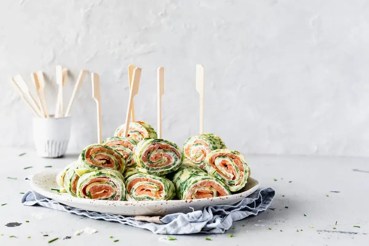 Leckere Spinat Lachs Rolle auf einem Teller, garniert mit Schnittlauch. Perfekt f&uuml;r jeden Anlass!