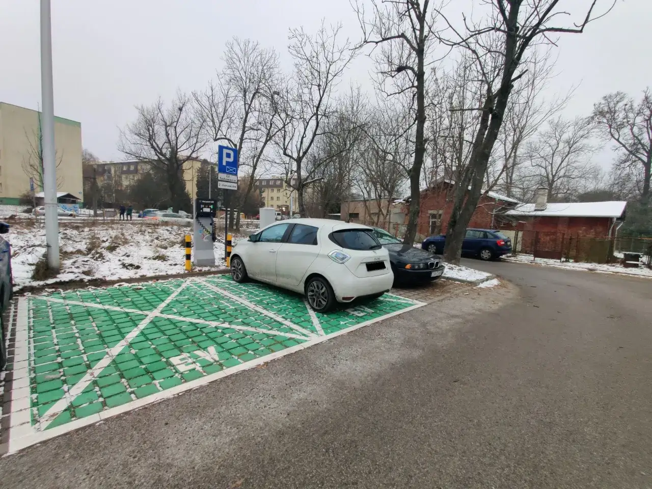 Stacja ładowania pojazdów elektrycznych w pobliżu PKP Łódź Widzew. Dwa samochody elektryczne czekają na naładowanie.