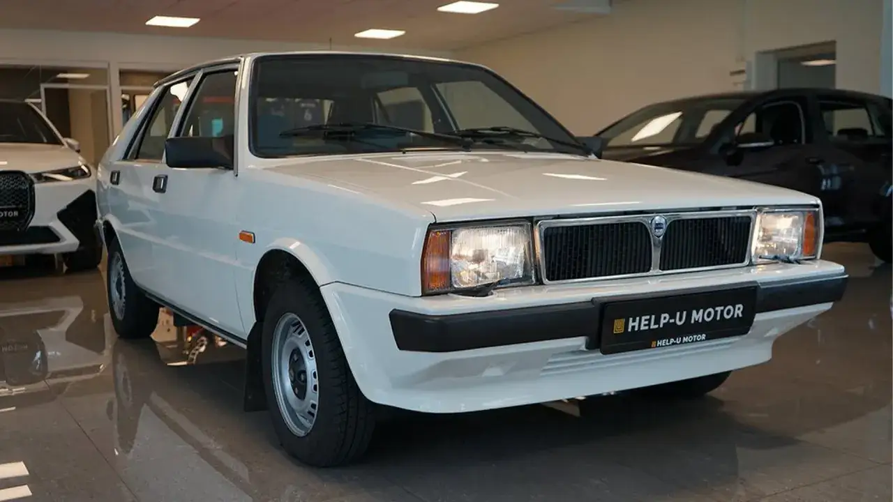 Vit Saab Lancia Delta i ett showroom. En klassisk bil som v&auml;cker nostalgi.