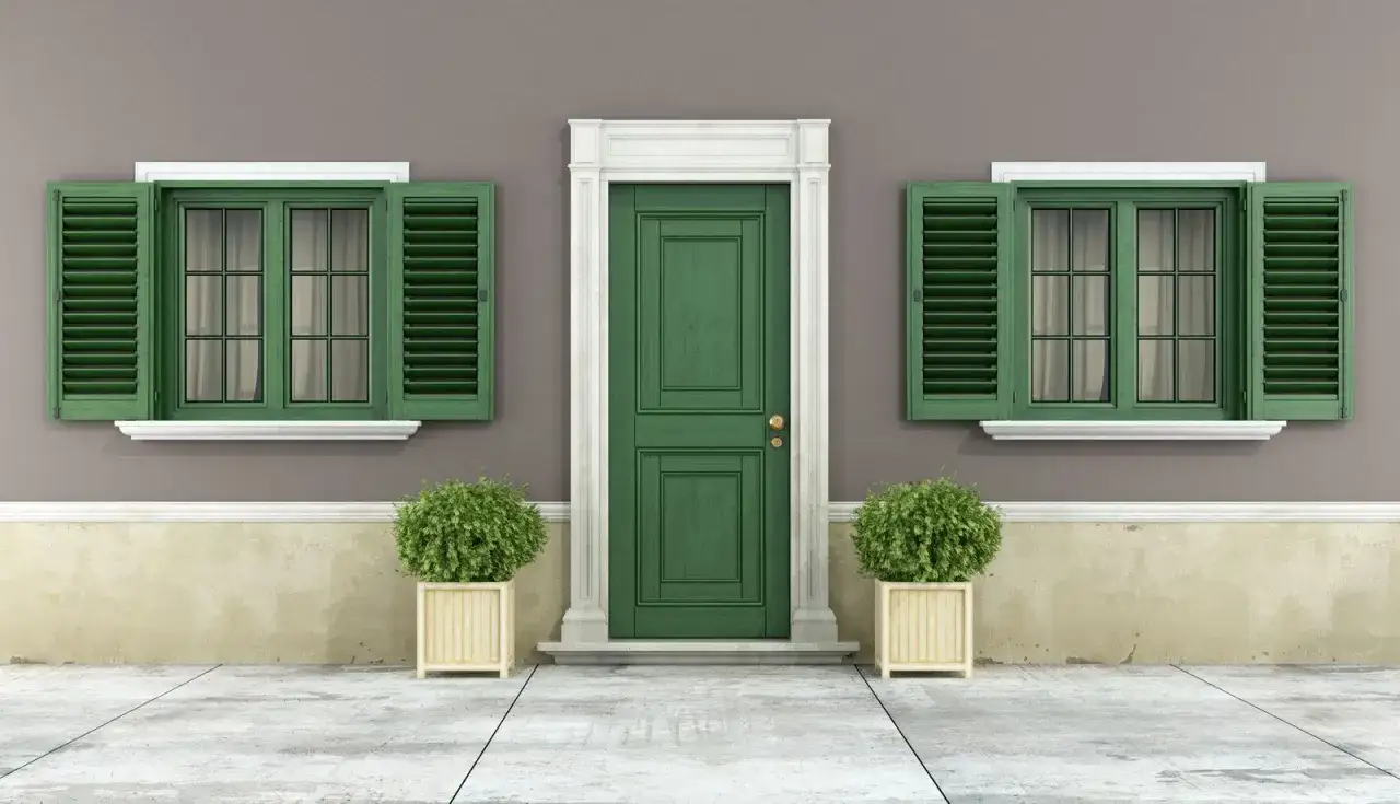 Fachada con puerta verde y ventanas a juego, ideal para una mejor pintura para exterior. Dos arbustos en macetas flanquean la entrada.