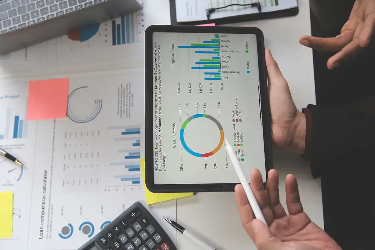 An&aacute;lisis de puestos de marketing digital con gr&aacute;ficos de presupuesto y gastos en una tablet.
