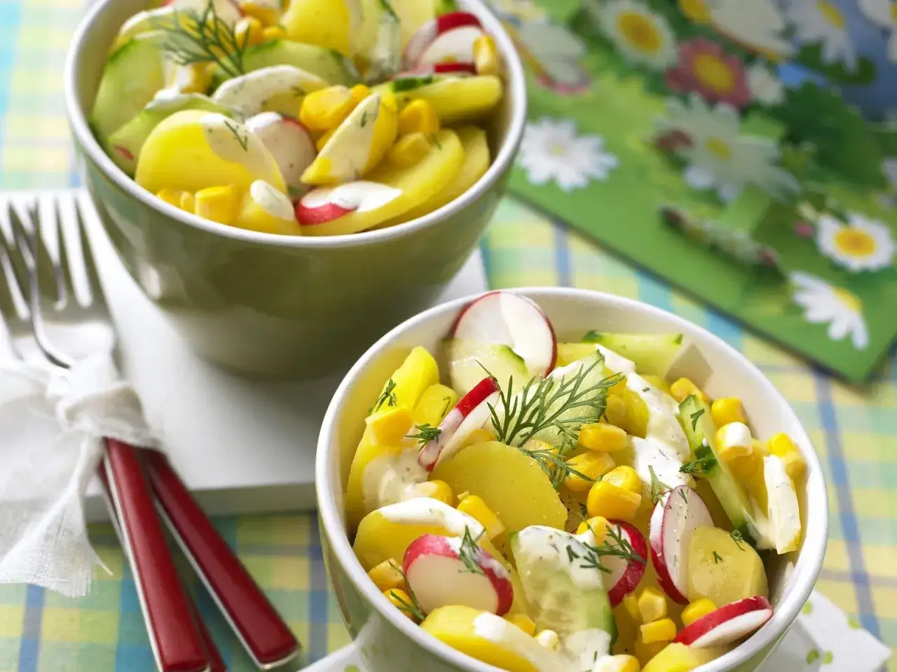 Kartoffelsalat mal anders: Bunte Kartoffelscheiben mit Radieschen, Gurke und Mais, verfeinert mit Dill und cremiger Soße.