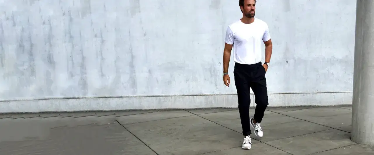 Man in a white t-shirt and black pants, embodying a perfect casual dress code.