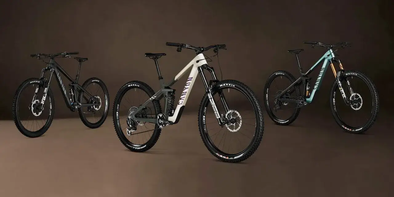 Three Canyon full-suspension mountain bikes: a black downhill bike, a cream and grey enduro bike, and a teal enduro bike, ready for any trail.