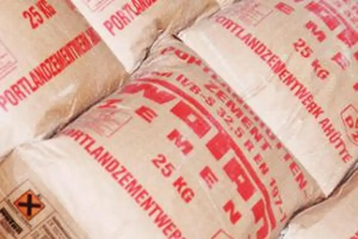 Stapel von 25 kg Säcken Portlandzement. Die Säcke sind mit roten Buchstaben bedruckt, die den Namen des Zementwerks und die Produktinformationen zeigen.