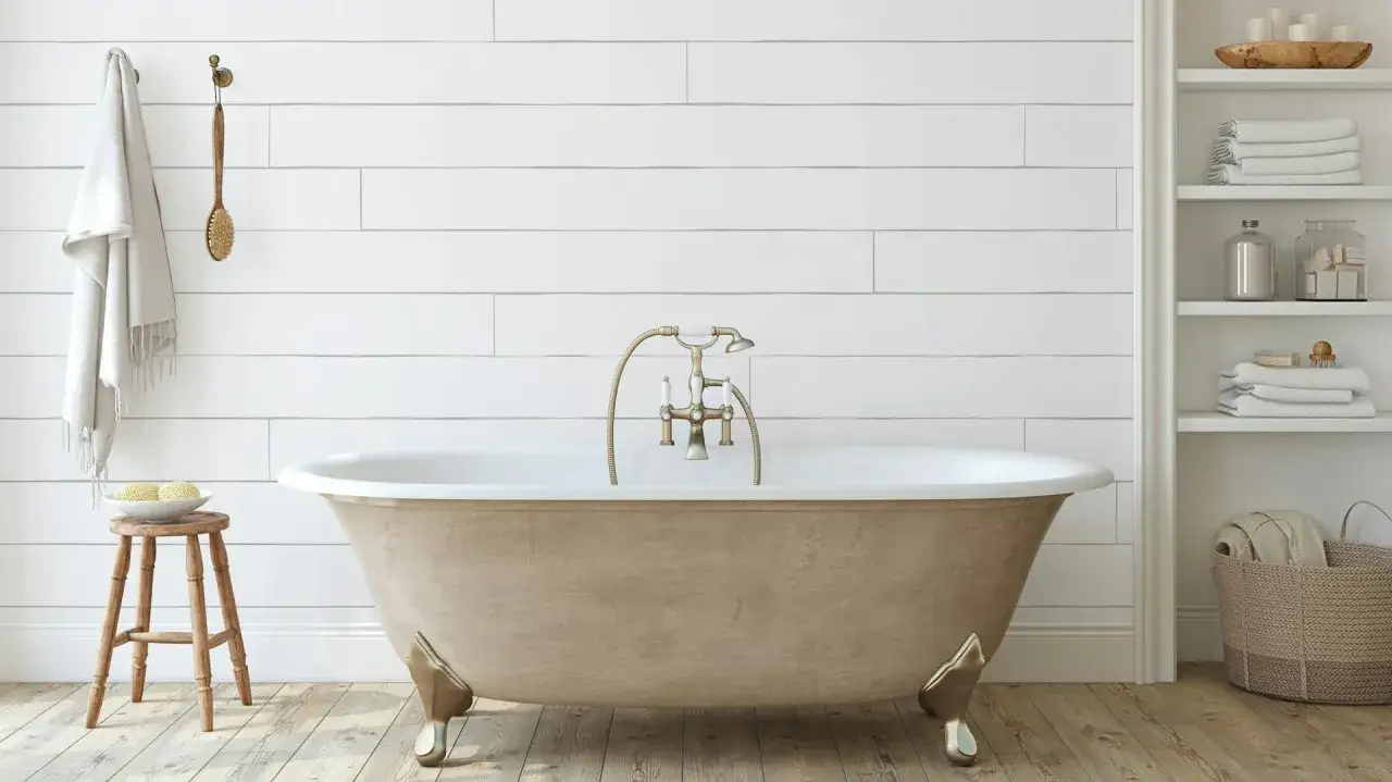 Bagno con vasca freestanding color sabbia, rubinetteria dorata e asciugamani bianchi. Ideale per chi vuole verniciare vasca da bagno.