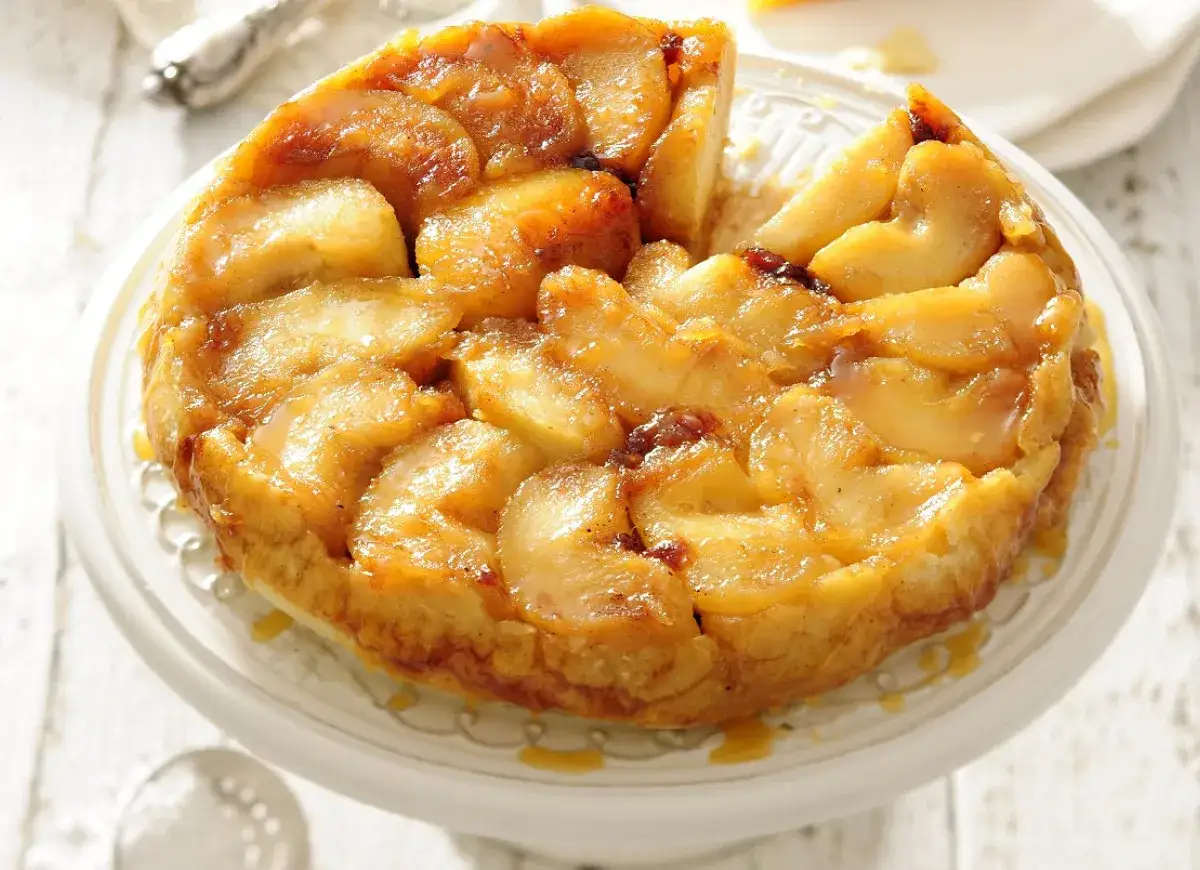 Apetyczna tarta tatin z karmelizowanymi jabłkami, której owoce pod kruszonką kuszą złotym kolorem.