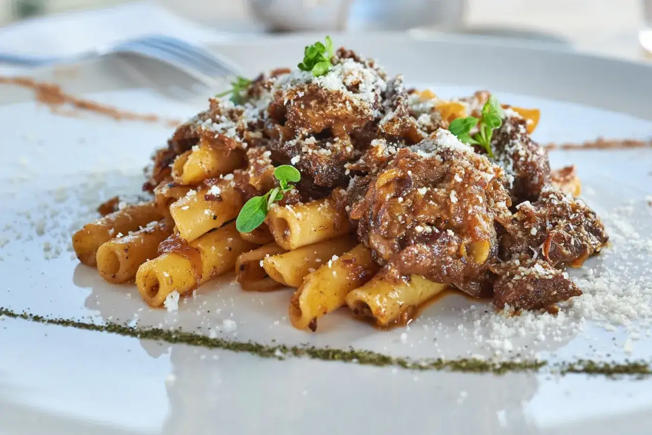 Ziti alla genovese, un piatto ricco e saporito con pasta e ragù di carne, guarnito con parmigiano e erbe aromatiche.