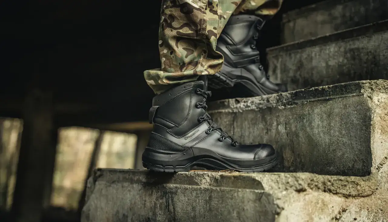 Czarne buty taktyczne Texar Stinger na schodach, w połączeniu z bojowymi spodniami w kamuflażu.