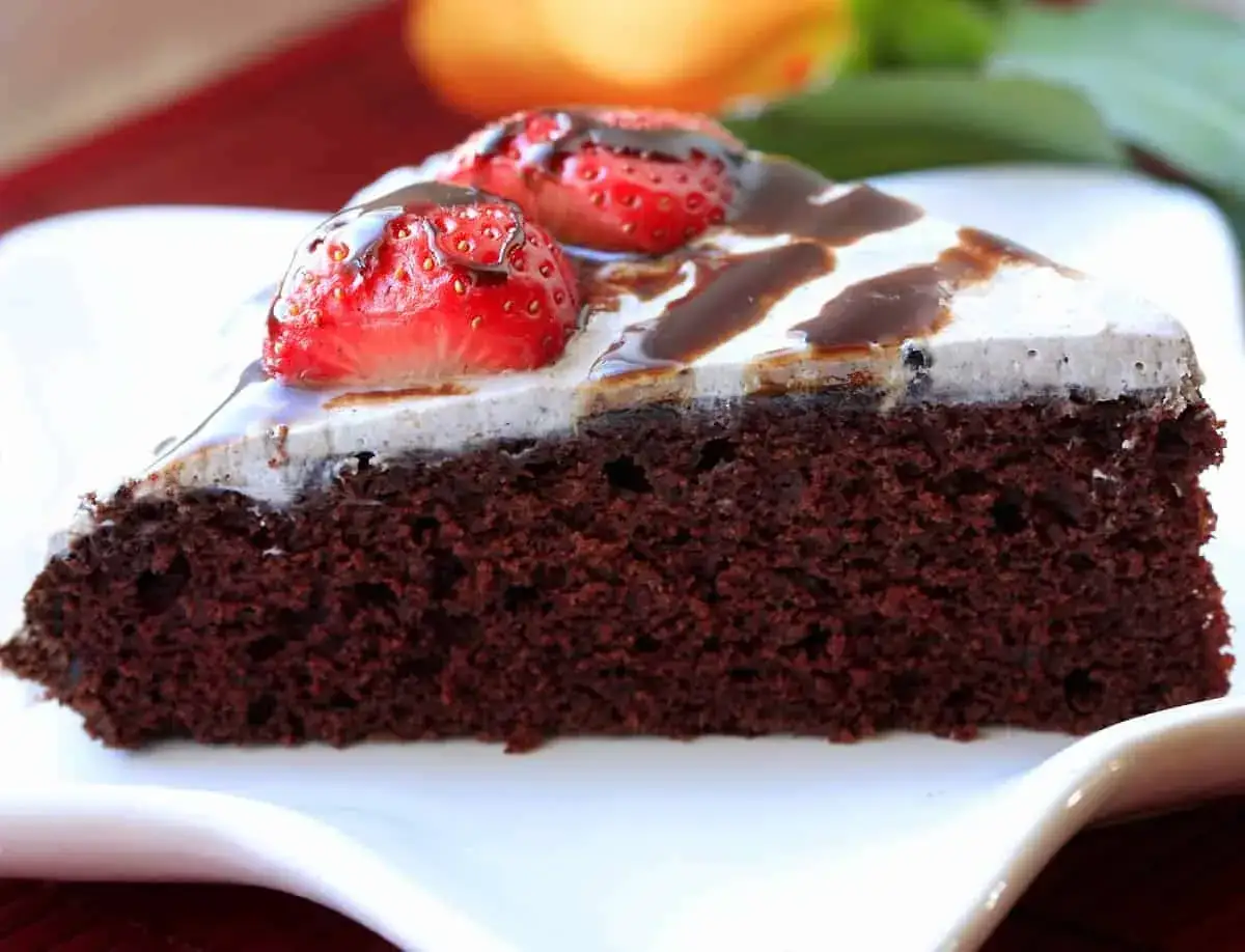 Deliciosa tarta vegana de chocolate, cubierta con crema y fresas frescas, bañada en sirope de chocolate.