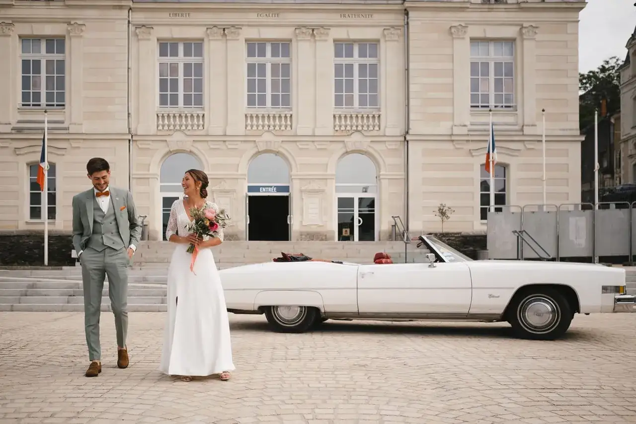 Un jeune couple rayonnant, tout juste mari&eacute; en ce mois de mai, pose devant la mairie avec leur voiture de r&ecirc;ve.