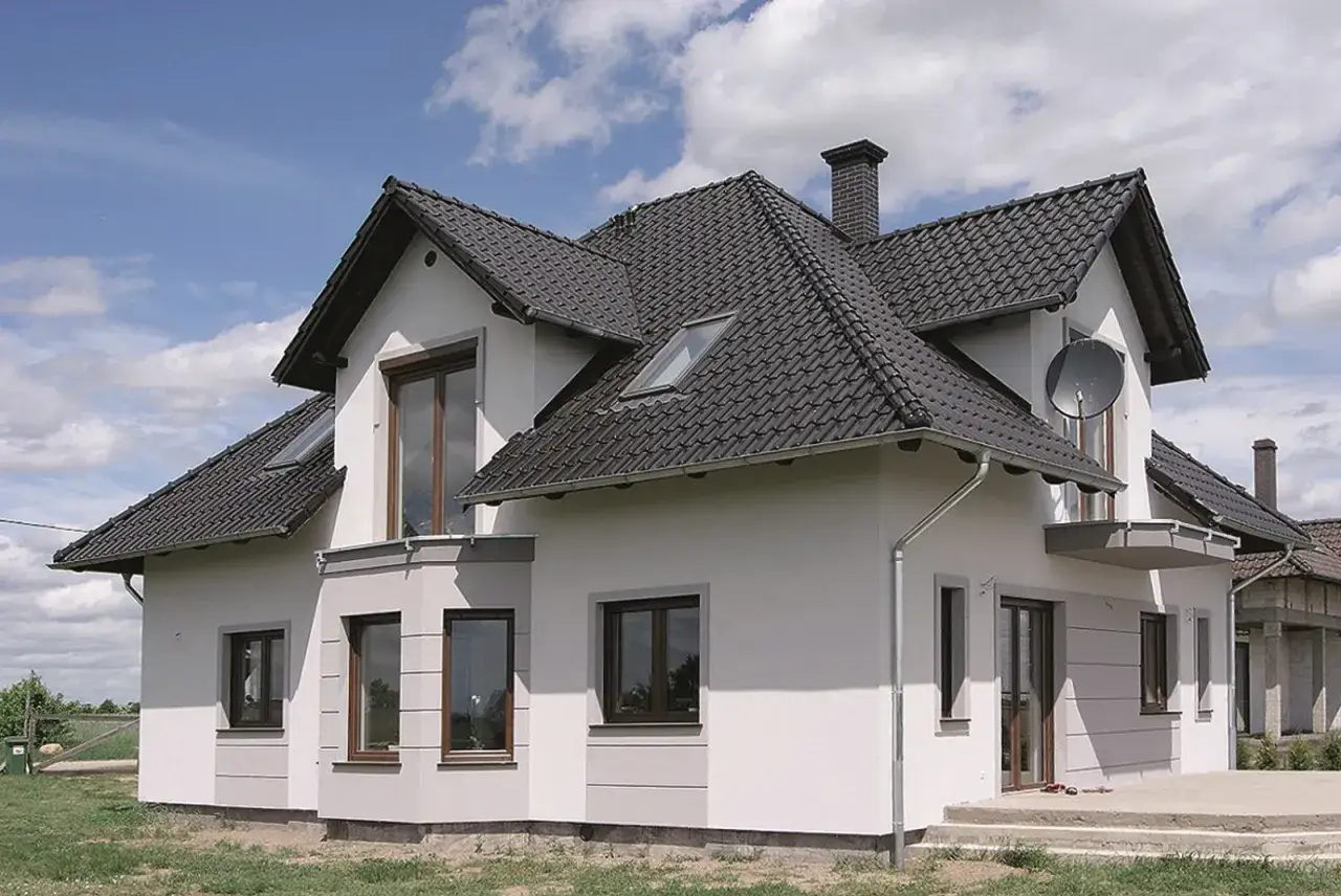 Nowoczesny dom z jasną, gładką strukturą elewacyjną, ciemnym dachem i brązowymi oknami.