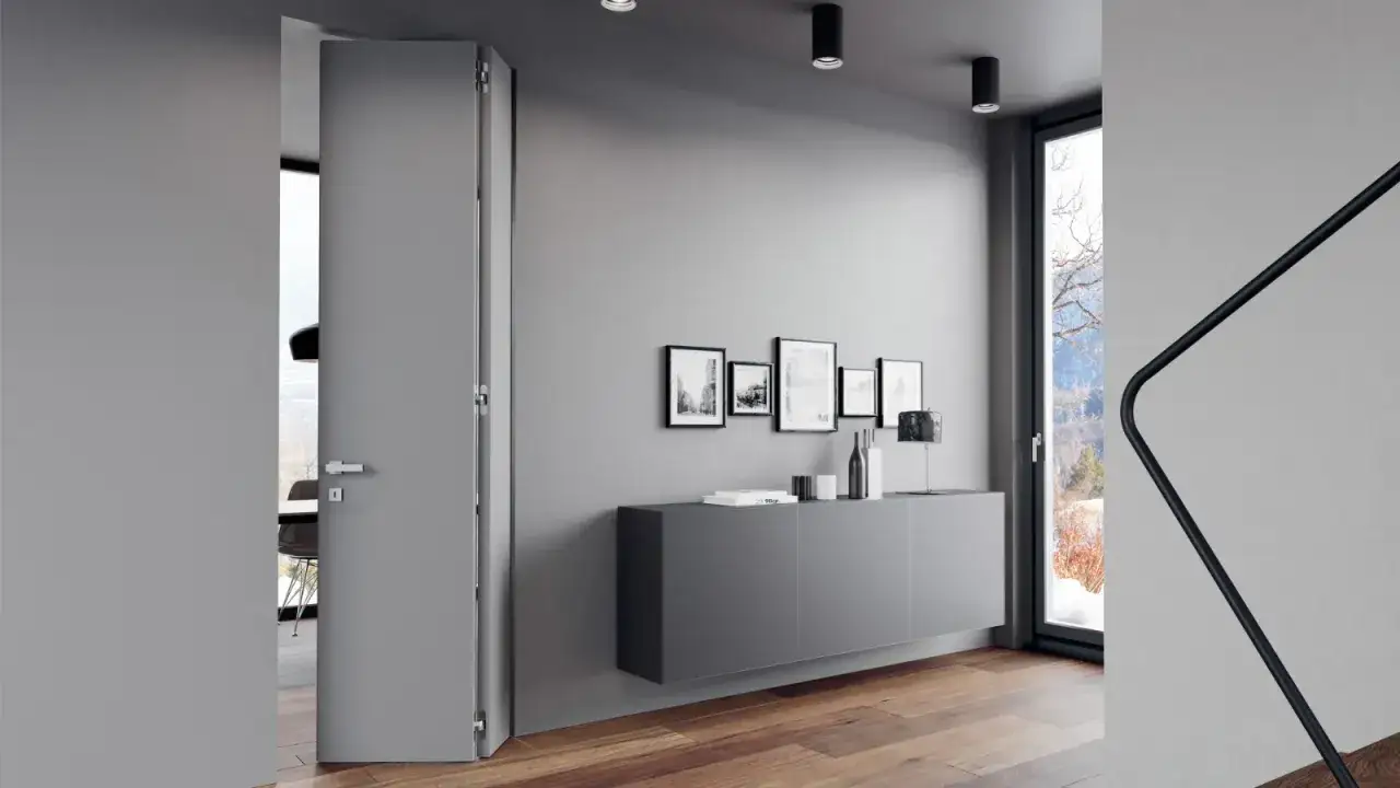 Un'elegante porta grigia si apre su un interno moderno. Diversi tipi di porte, come questa a battente, definiscono gli spazi.