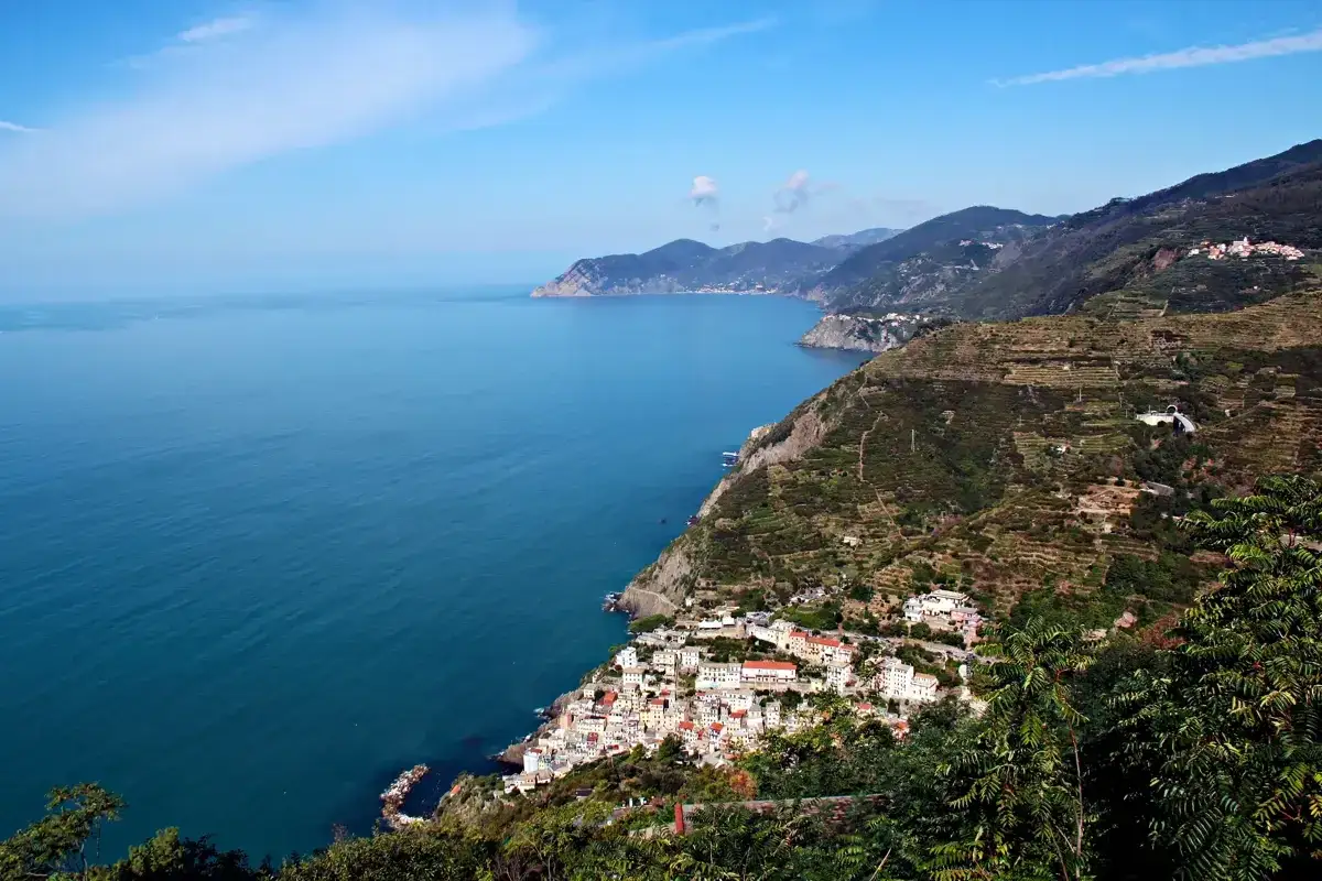 Bunte Häuser schmiegen sich an steile Hänge der Cinque Terre, umgeben von terrassierten Weinbergen und dem tiefblauen Ligurischen Meer.