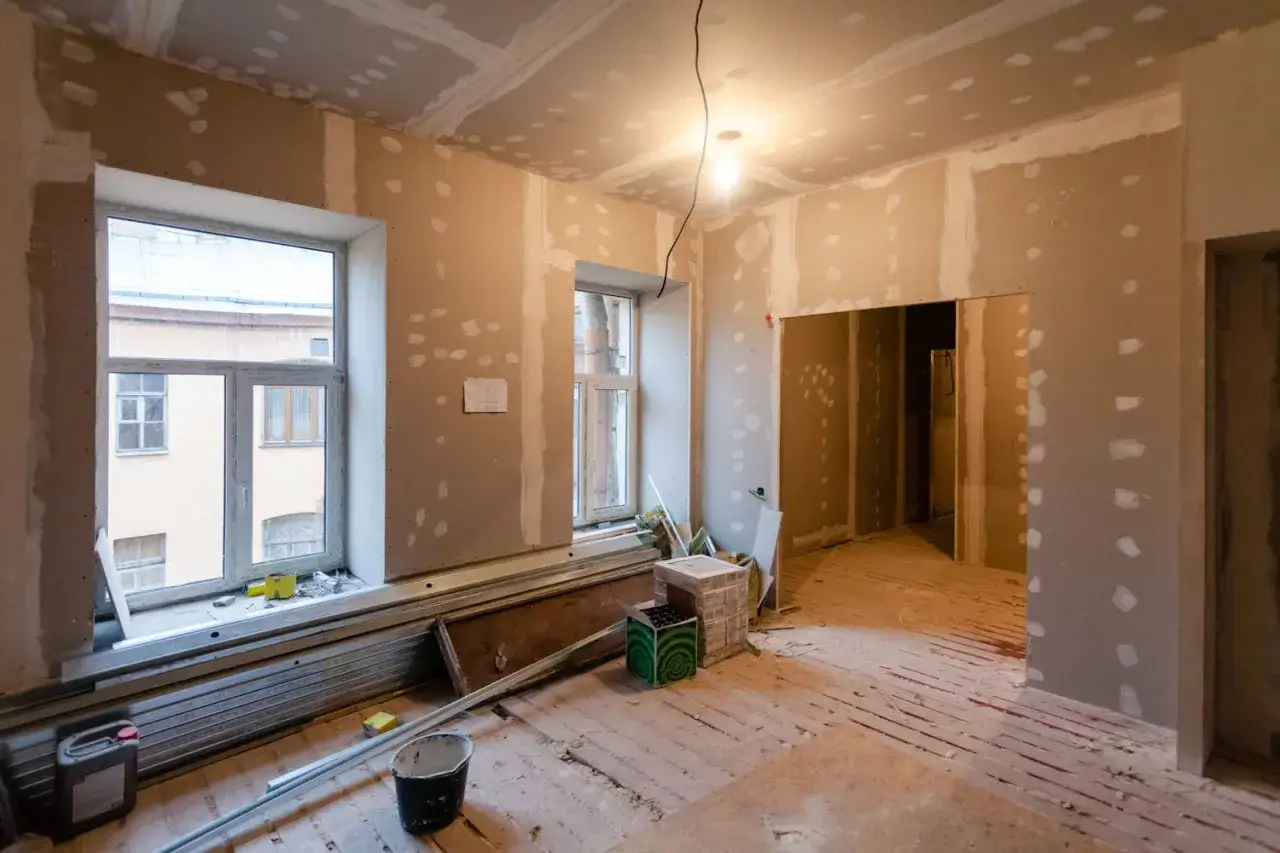 Chantier intérieur, murs en cours de finition, prêt pour la loi Denormandie 2024. Matériaux de construction au sol.