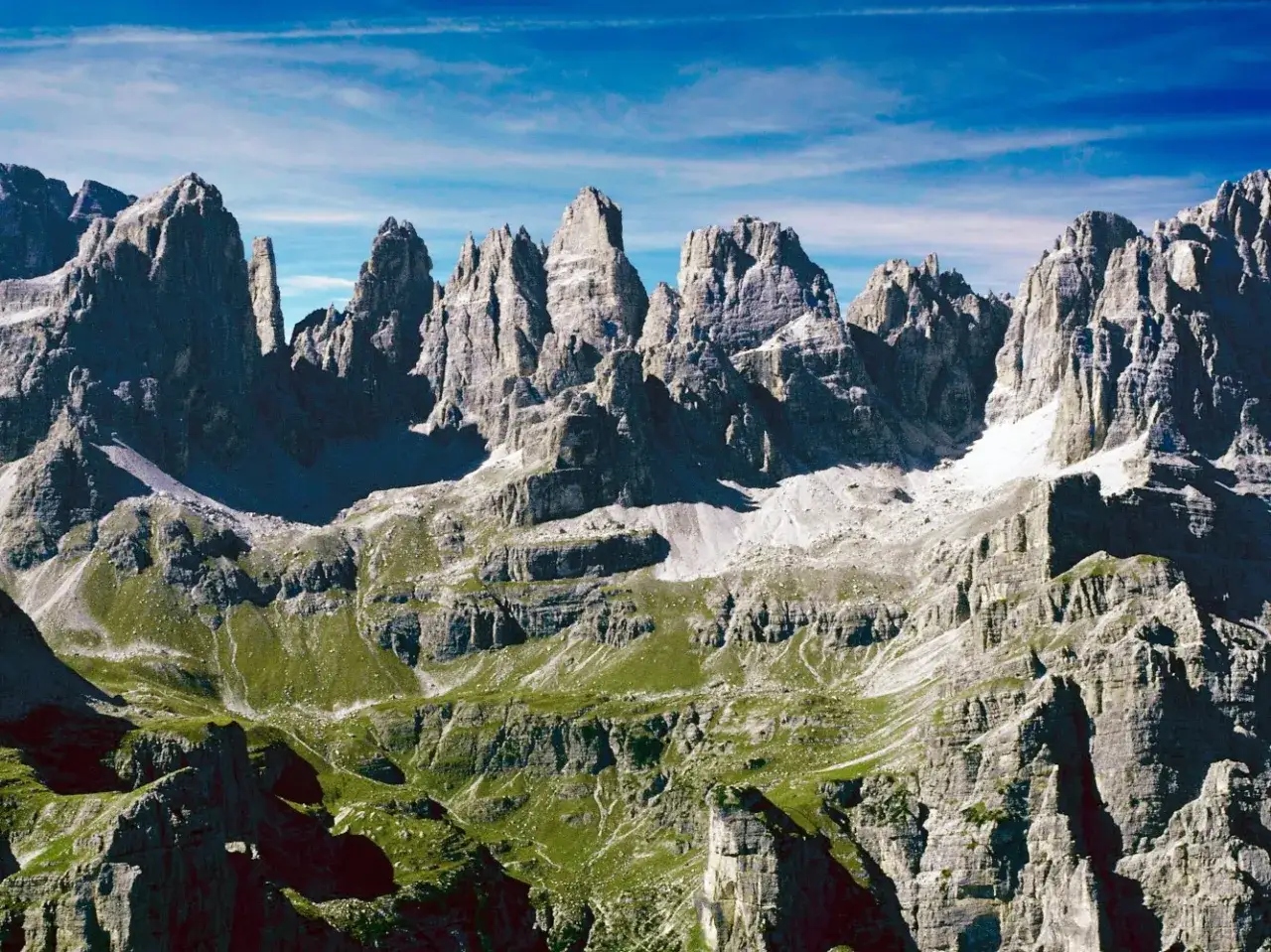 Cime rocciose imponenti e verdi pendii alpini, un paesaggio mozzafiato ideale per le **ferrate Trentino**.