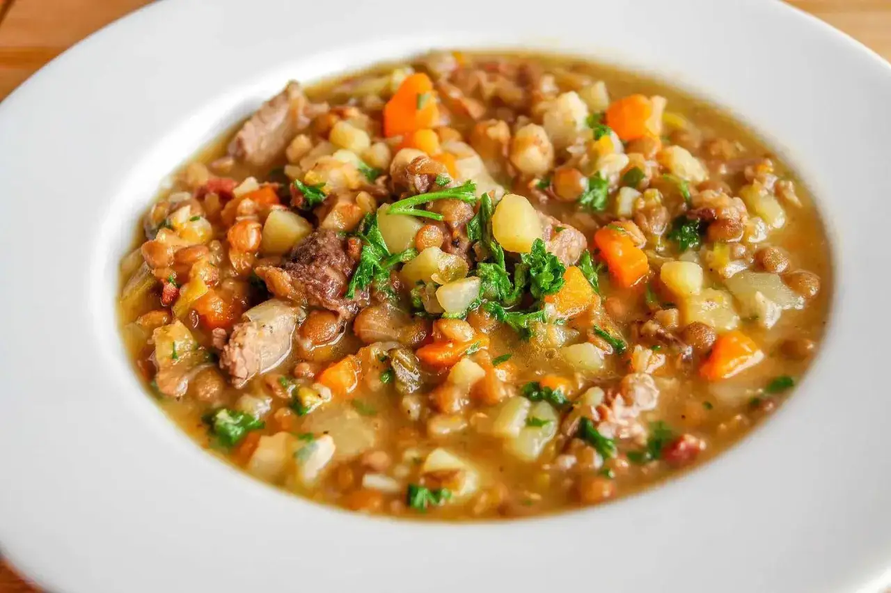 Un plato de lentejas estofadas estilo Argui&ntilde;ano, con trozos de carne, patatas, zanahoria y perejil fresco.