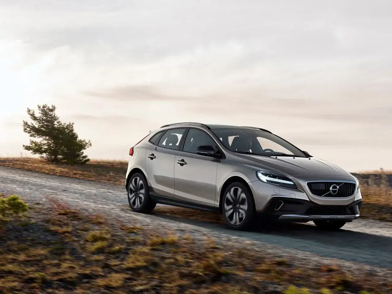 Srebrne Volvo V40 Cross Country jedzie po szutrowej drodze. Rozmiar opon jest idealny do jazdy w terenie.