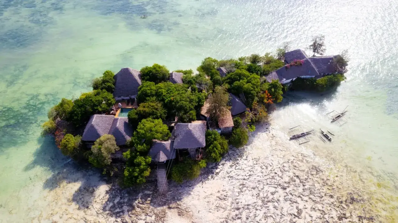 Rajska wysepka na Zanzibarze. Warto wiedzieć, że to idealne miejsce na relaks, z domkami krytymi strzechą i łodziami czekającymi na wodzie.