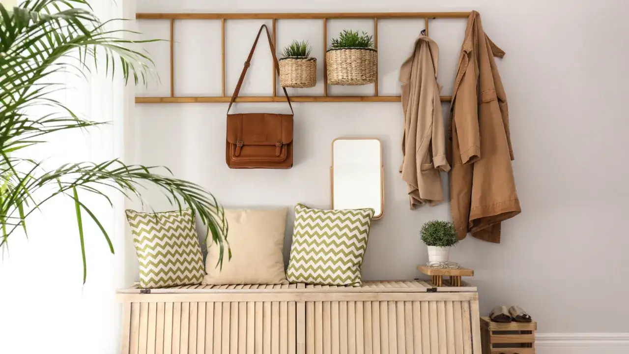 Une entrée chaleureuse avec des paniers en osier, un sac en cuir, des coussins graphiques et des manteaux. Une belle idee deco entree de maison naturelle et fonctionnelle.