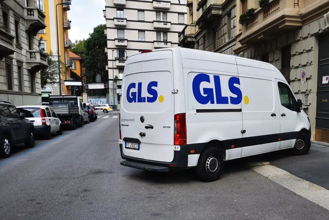 Furgone GLS bianco parcheggiato in strada. Un corriere GLS lavora sodo per consegnare pacchi, sperando in un buon stipendio.