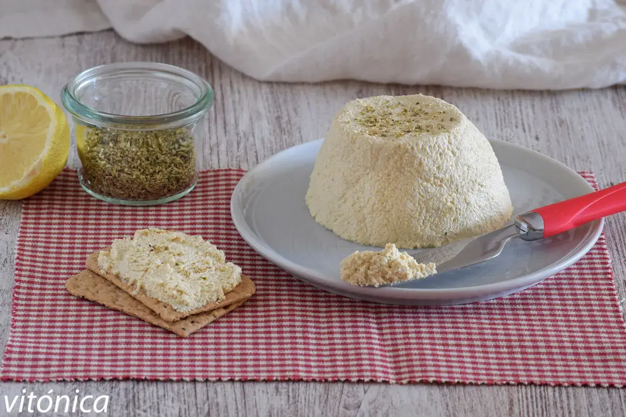 Deliciosa ricotta vegana con hierbas, servida sobre galletas y acompañada de limón y especias.