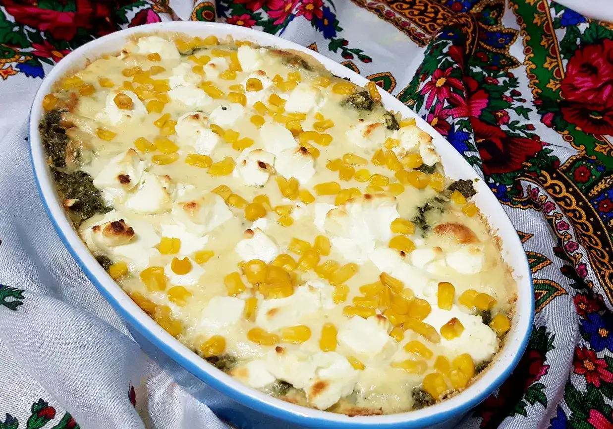 Zapiekana lasagne ze szpinakiem, polana kremowym sosem, z kawałkami sera feta i kukurydzy.